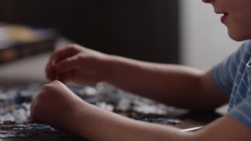 A boy laughs while putting together a jigsaw puzzle