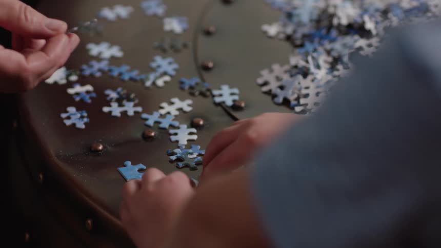 A man puts a jigsaw puzzle together with his son