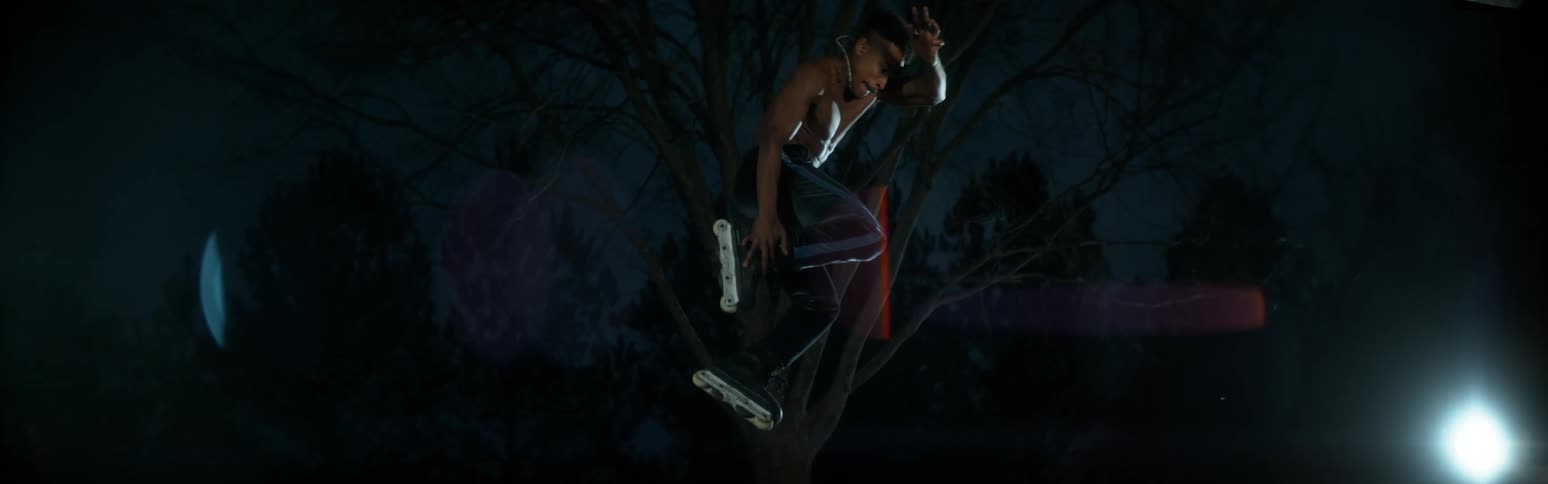 Barechested male rollerblader twists while leaping through air at night