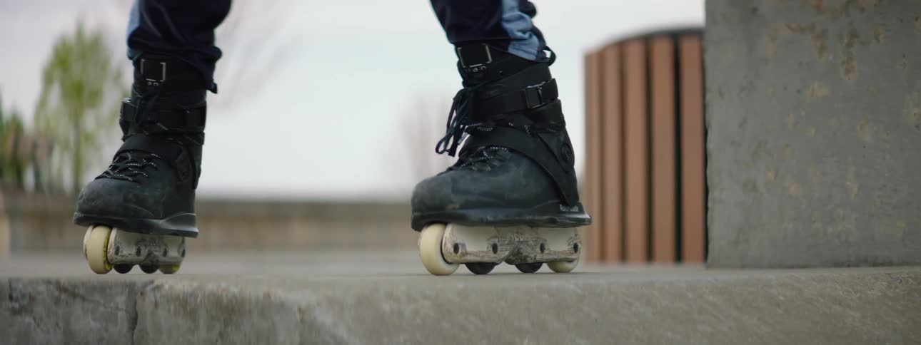 The feet of a person coming to a stop after roller skating outdoors in a skate park on an overcast day