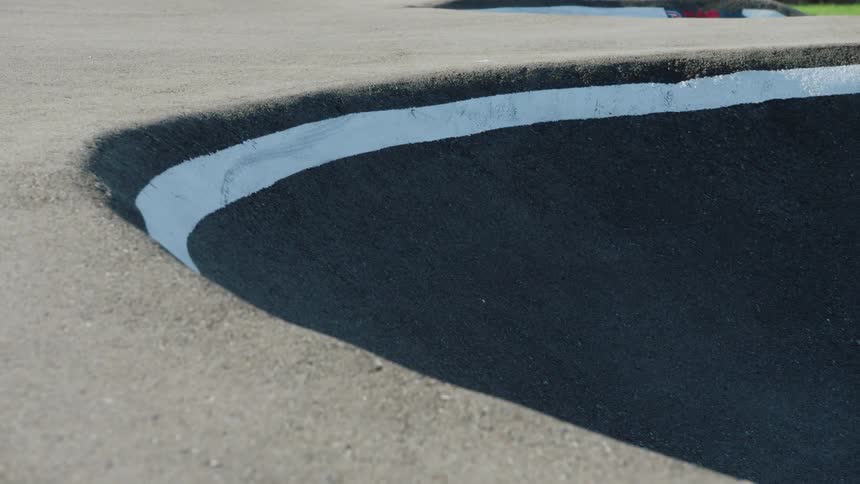 Person rides bmx bike along wall of bowl in park