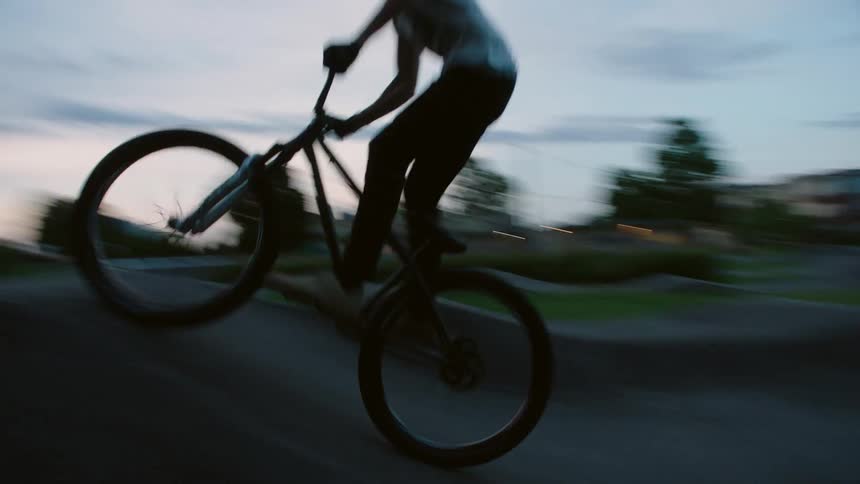 A man rides a bicycle down a ramp at a skate park