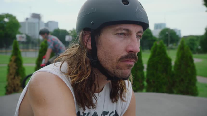 A man sits as someone rides a bicycle