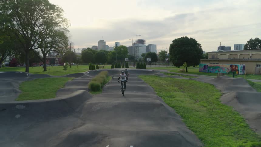 Two cyclists jumping and driving motocross bicycles on a beautiful small track on a park