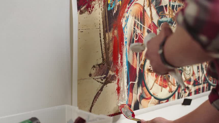 Close up of an artist painting on a large canvas with oils on a wall