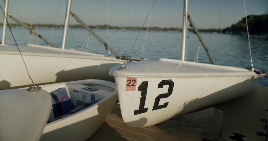 White sailboats on a pier at a lake in the morning