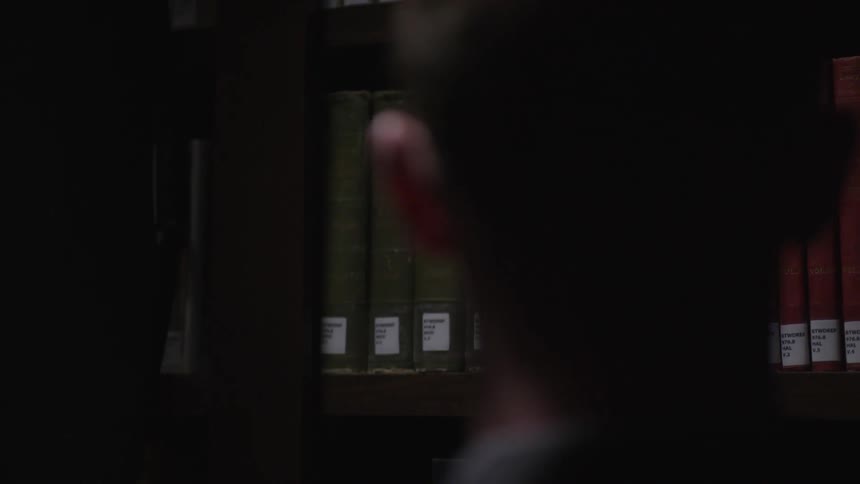 Man removing a book from a shelf and looking through it