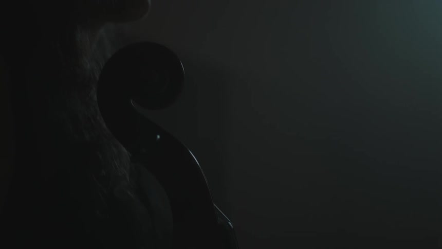 A woman holds an instrument in a dark room