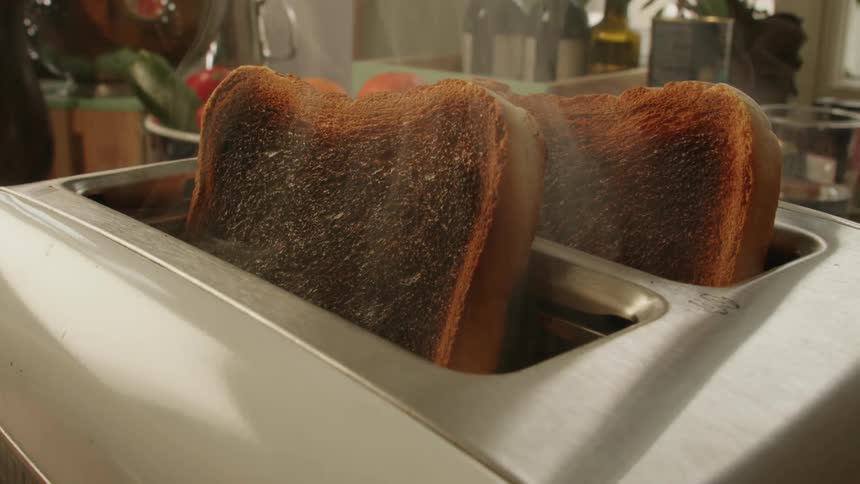 Smoke rises from a toaster on a kitchen counter as burnt toast pops up