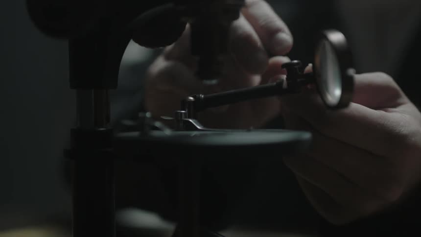 A man adjusts a microscope