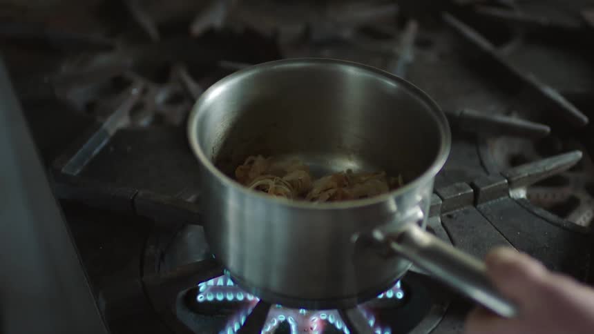 A person is cooking noodles on the stove