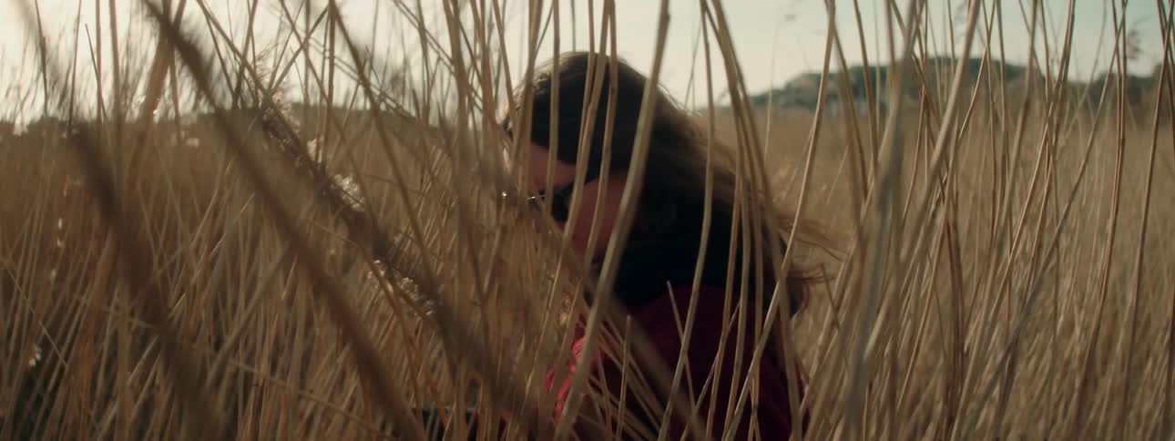 A woman is walking through the tall grass