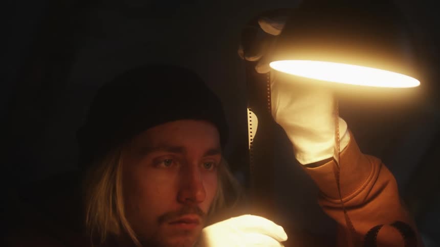 An up close of a mans face while he holds picture film in his hands wearing gloves