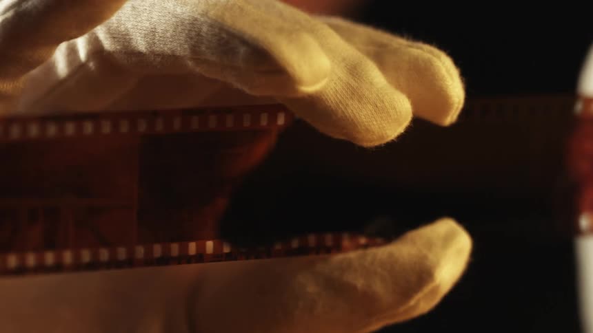 Close up of a person holding film negative in his hands with gloves on in the darkroom