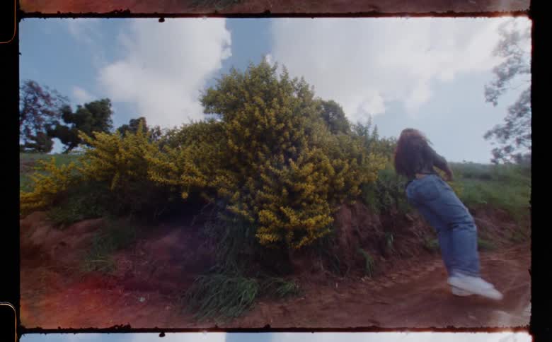 Young woman standing in the countryside dancing in front of the camera caught on vintage film
