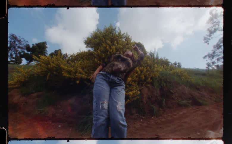 Young woman standing in the countryside dancing in front of the camera caught on vintage film