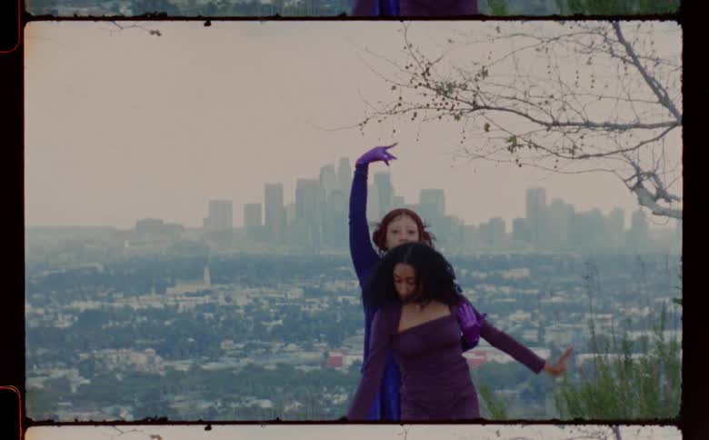 Two women move through dance routine on hill overlooking foggy city scape