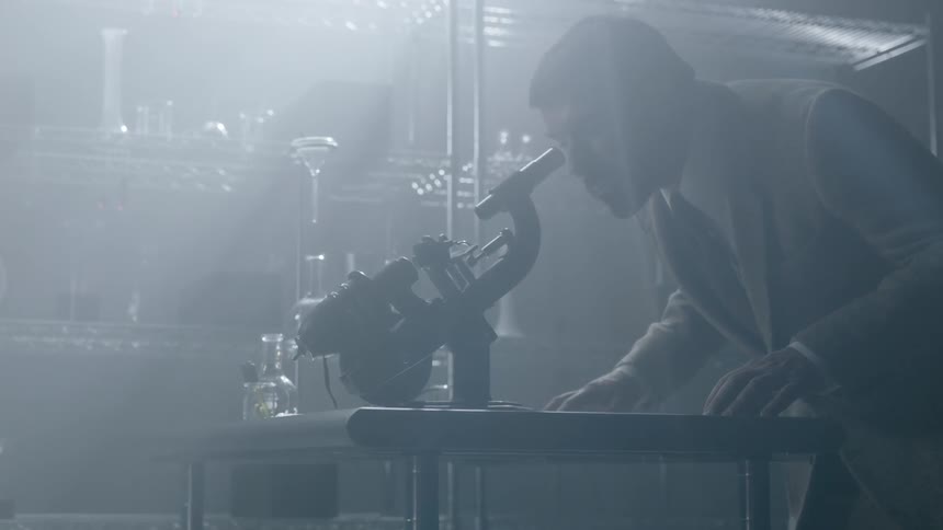 A man leans over to use a microscope