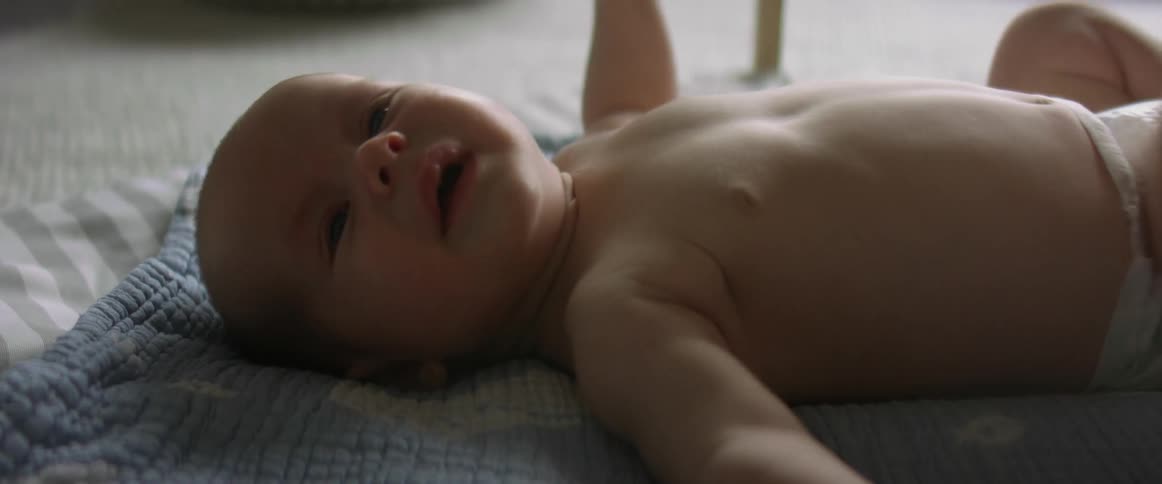 Baby son lies in baby gym crying