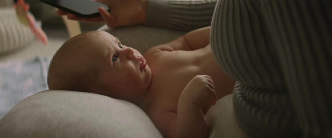 A mother uses her phone by the baby