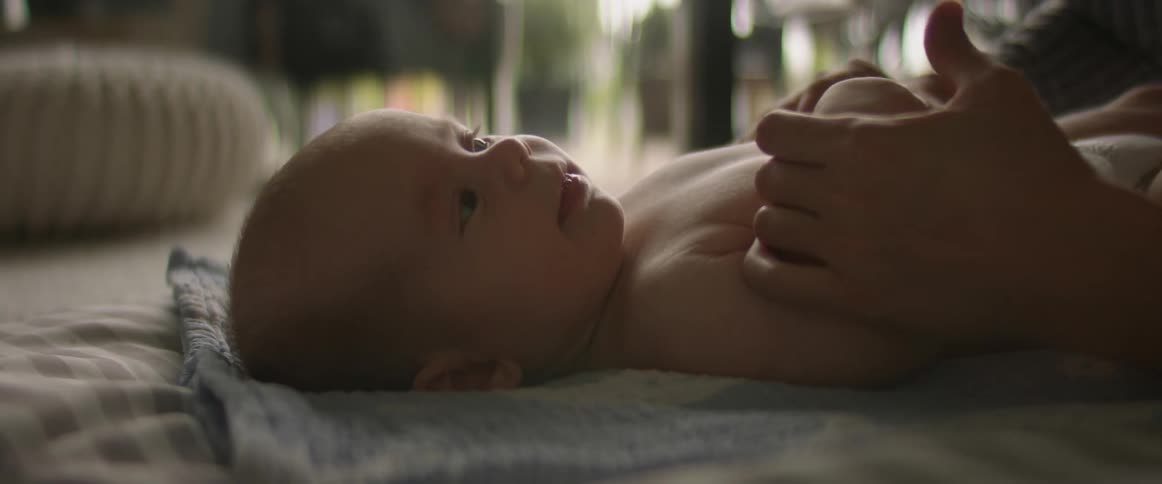 Mother engaging with baby on the bed holding hands baby smiling