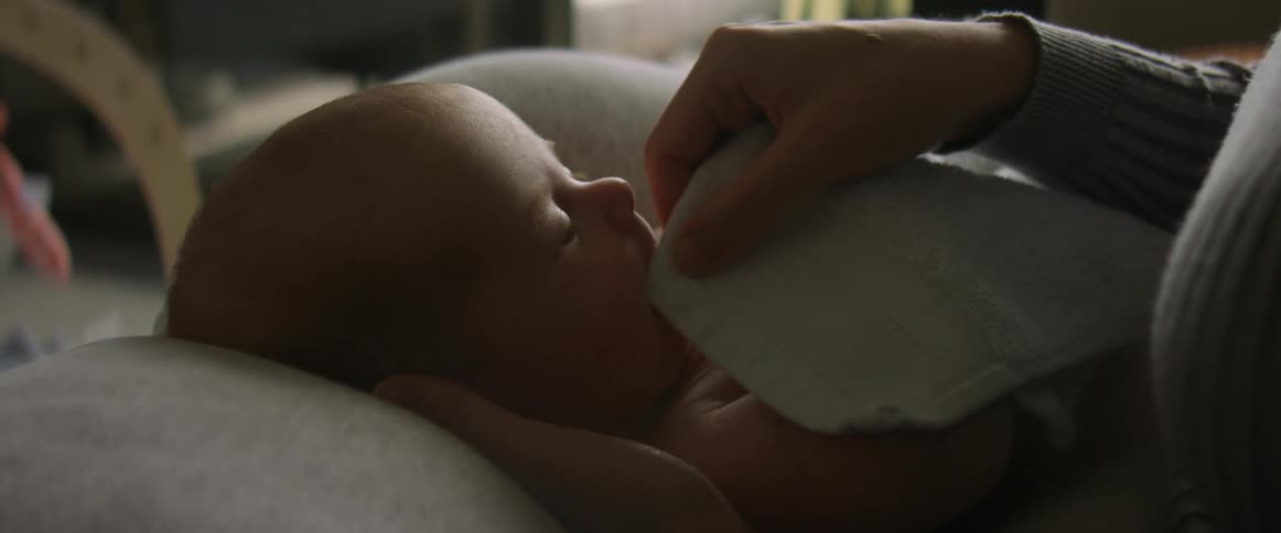 Mother with green shirt holds baby son in the living room