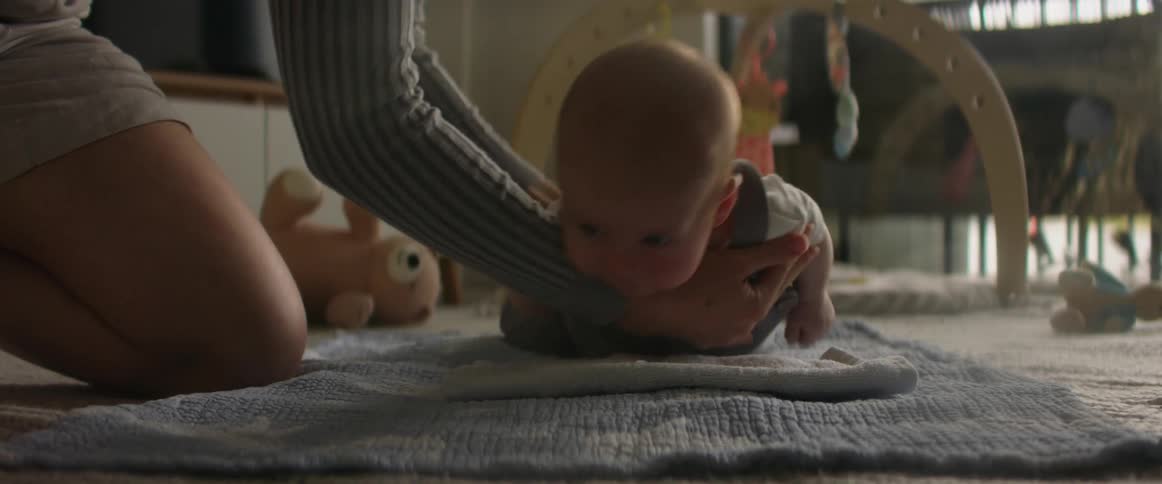 Baby being rolled over onto tummy on floor for tummy time