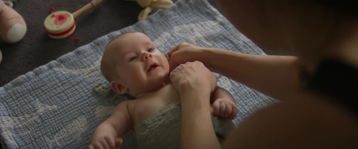 A mother is dressing her baby