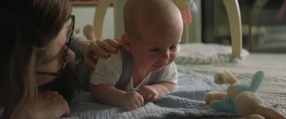 A mother and baby on the floor as the baby cries and the mother rubs the babies back