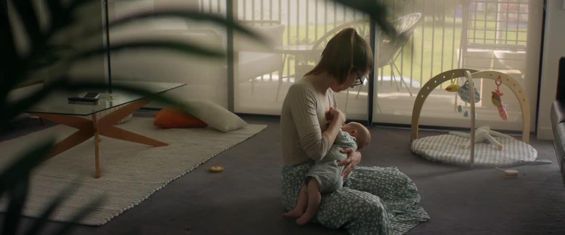 Mother sitting on living room breastfeeding baby