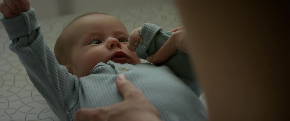 Mother plays with baby lying on surface
