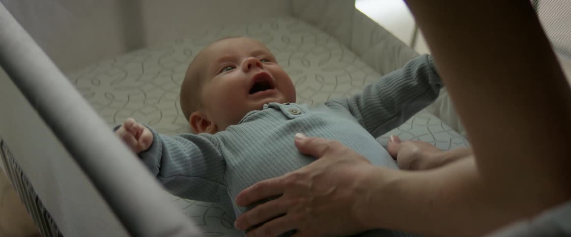 Happy baby wiggles and moves in baby crib