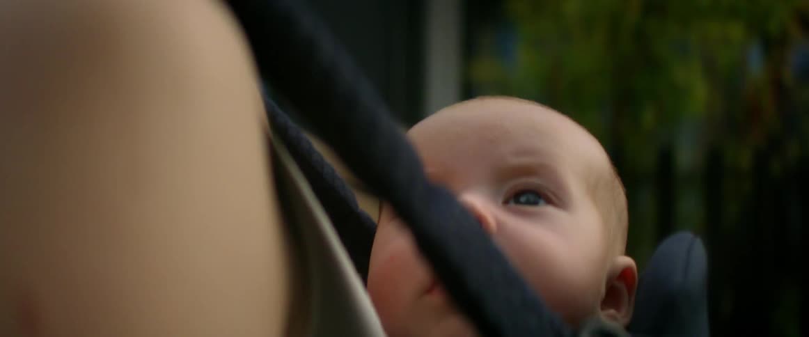 Mother walks past picket fence with child in baby carrier