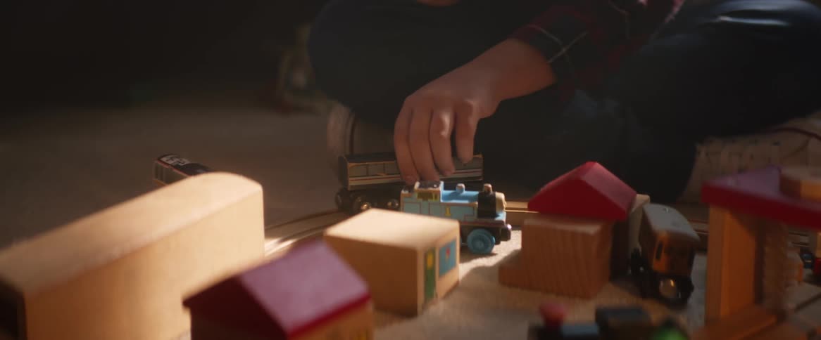 Child plays with toy vehicle and a toy town