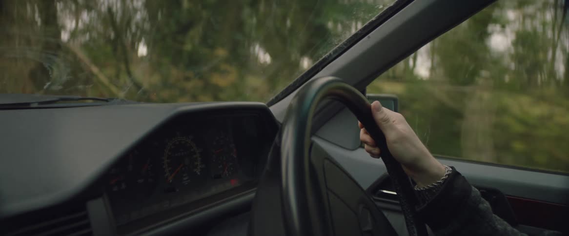 Interior view of persons hand on steering wheel while driving car
