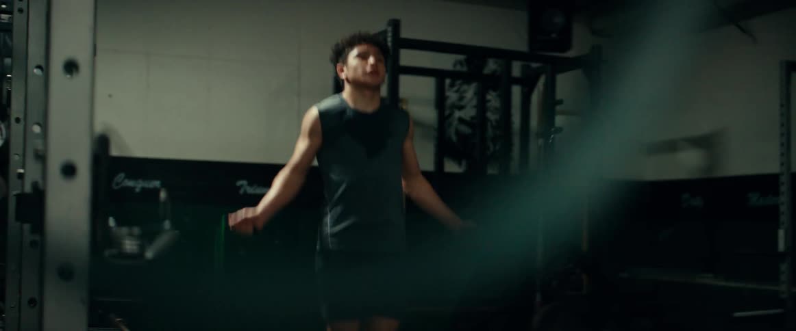 A man jumping rope in a gymnasium in a cut off shirt