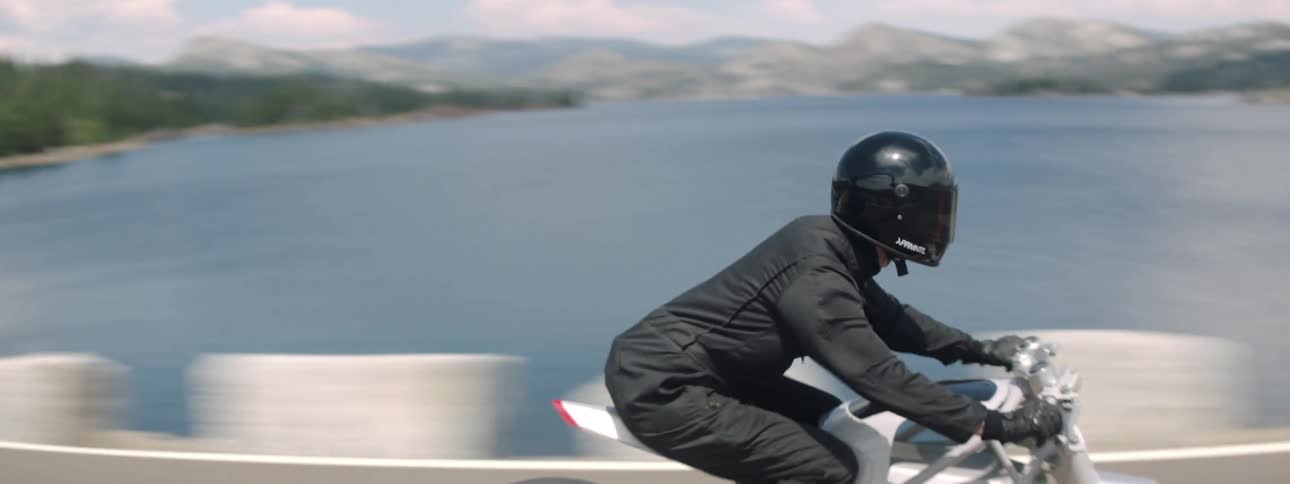A person rides their motorcycle over the bridge