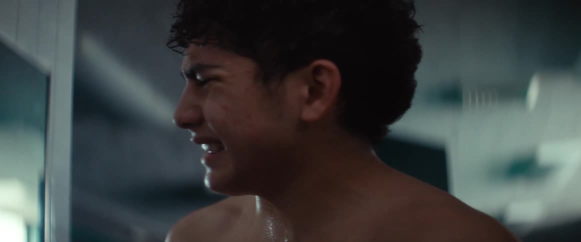 A man without a shirt on holding his side with a painful expression on his face
