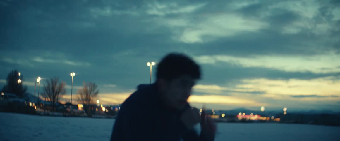 A teenage boy throws punches as he practices martial arts outside as the sun sets