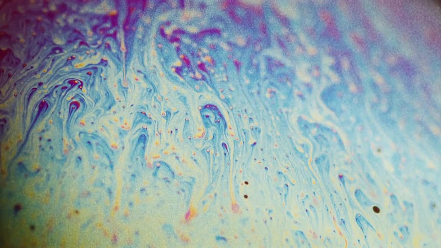 Particles are moving across colors leaving a blending trail behind as they float through the organic mixture