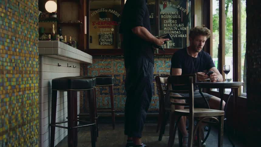 A man sitting at a cafe table as the waiter takes his card to pay