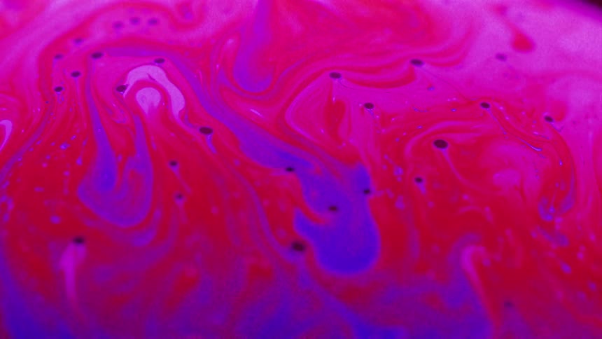 Bright pink and purple liquid flows to the left and creates mixed colorful swirls
