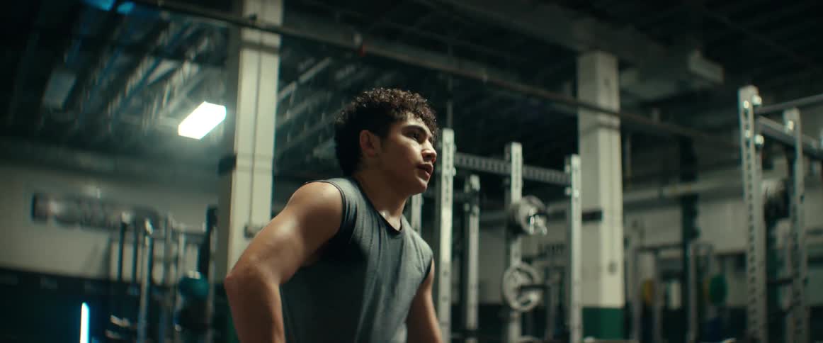Muscular man with gray shirt and red shorts rests in the gym