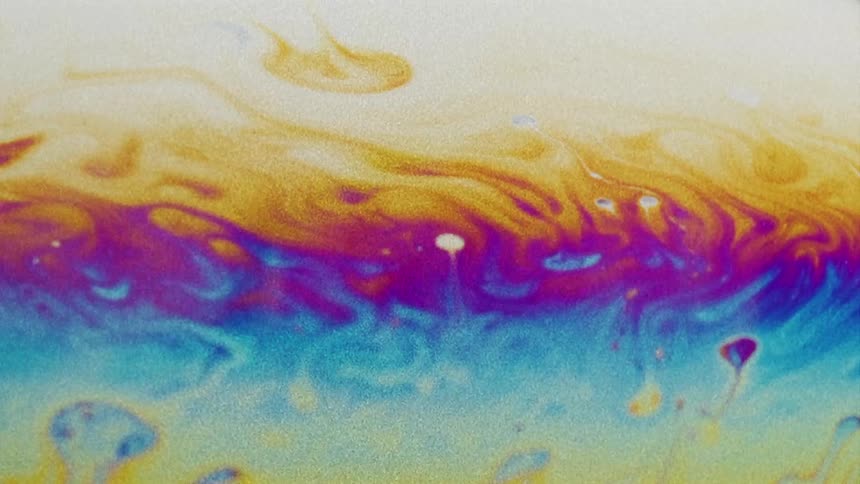 Fluorescent colors move and blend as particles of color stretch across the warping mixed surface