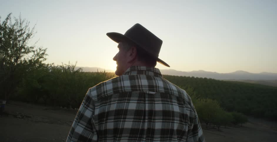 A man is standing outdoors while the sun is setting
