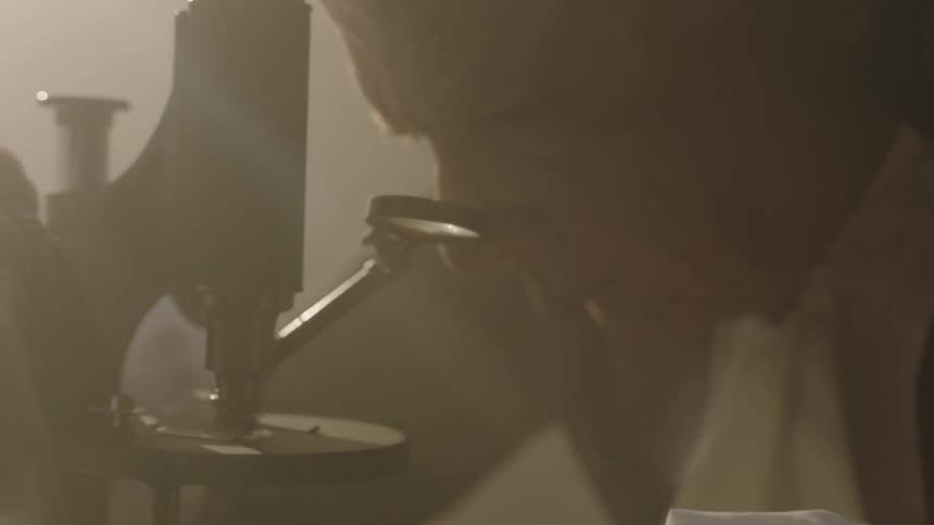 A man is looking through a microscope