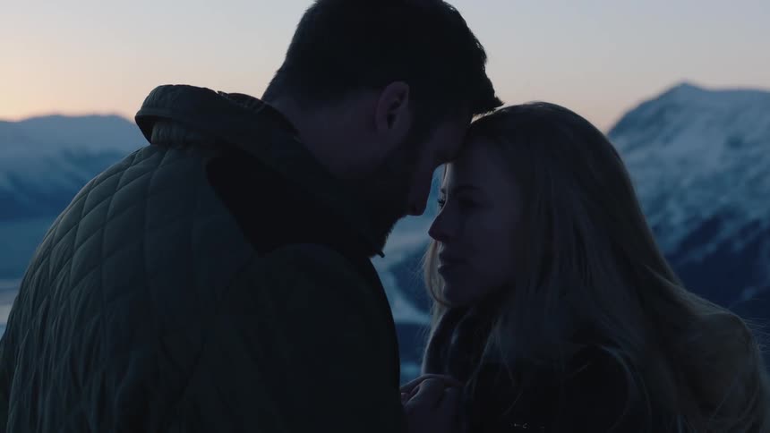 A man and woman nuzzling and talking before looking at a view