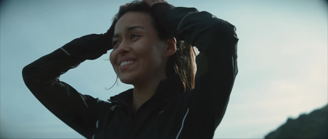 A worried looking teenage girl runs her hands through her hair and then smiles and laughs