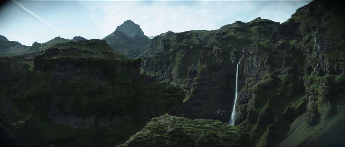 A waterfall crashes down a mountain range