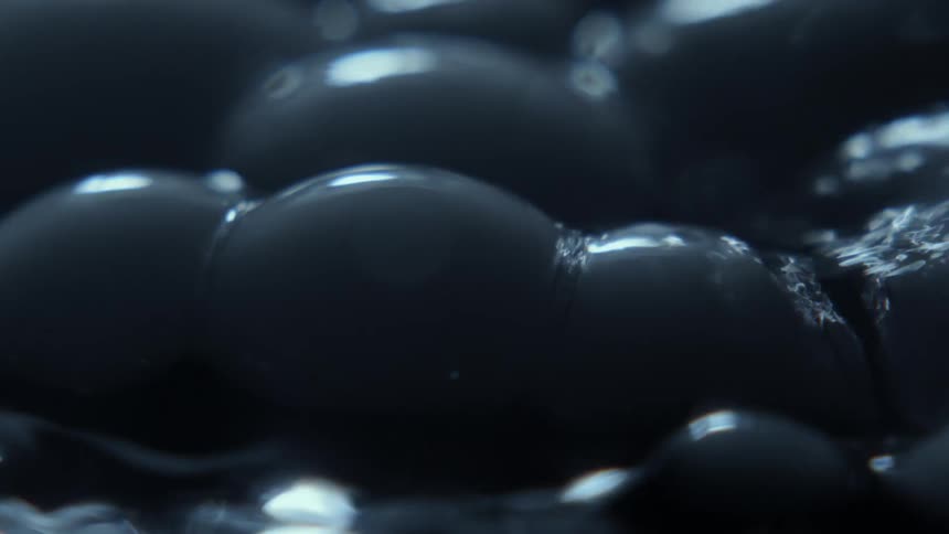 A thick gray liquid bubbles up on the surface